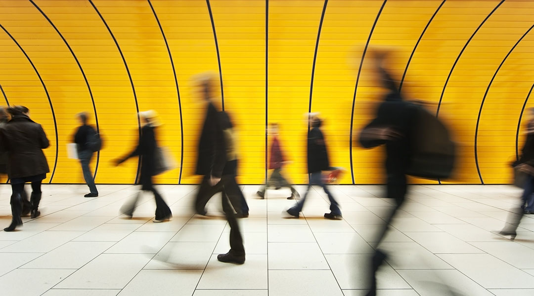 People blurry in motion in yellow tunnel down hallway