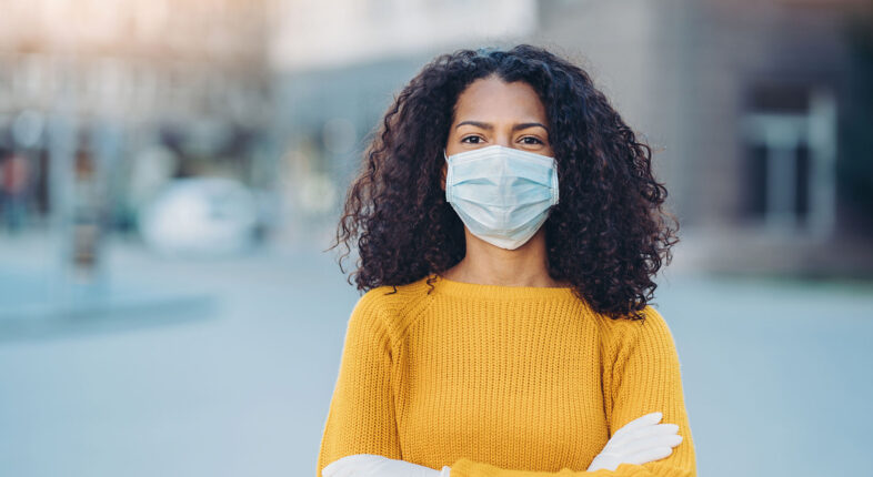 Portrait of a young woman with face mask outdoors in the city